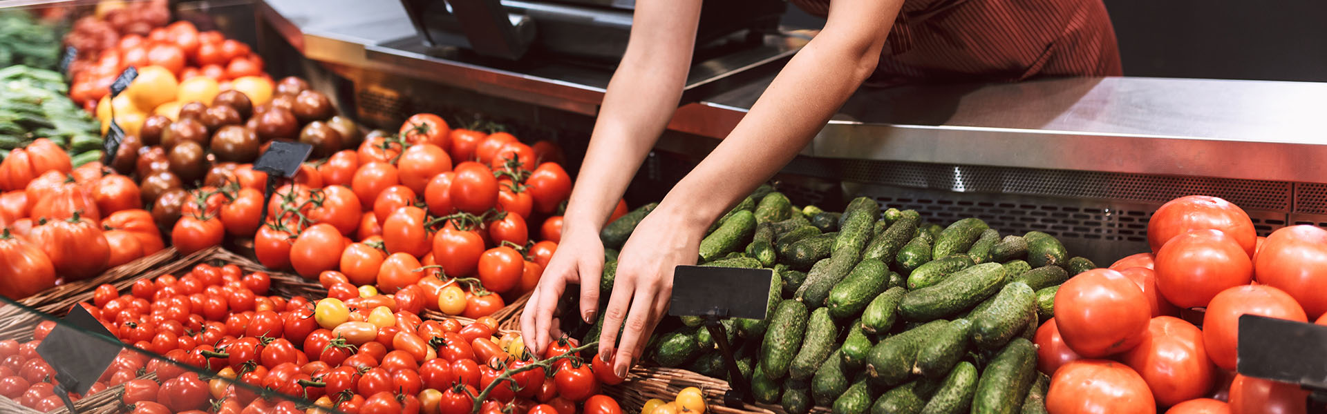Mitarbeiterin im Supermarkt am Gemüsefach